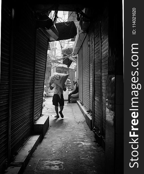 Grayscale Photo of Man Carrying Sack