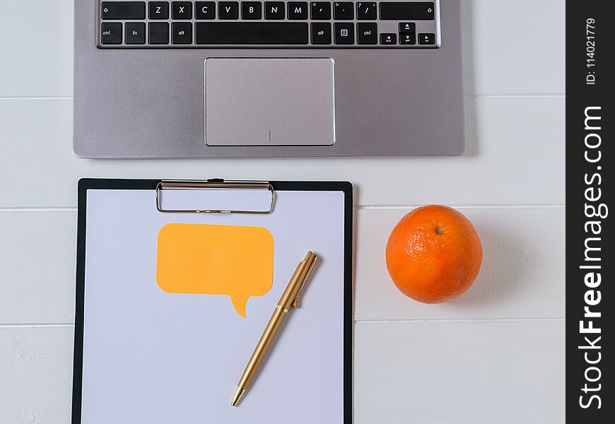 Place for text on tablet with paper, laptop and orange on white table. The concept of modern education. Place for text on tablet with paper, laptop and orange on white table. The concept of modern education.