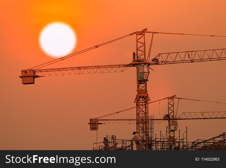 Building and crane under construction with sunrise or sunset sky background