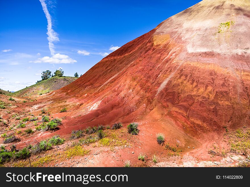 One of the Oregon Painted Hills. Bold red sandy soil makes a single hill, topped with a light tan colored soil. One of the Oregon Painted Hills. Bold red sandy soil makes a single hill, topped with a light tan colored soil.