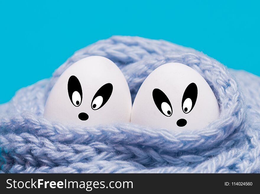Two white eggs wrapped in a knitted scarf