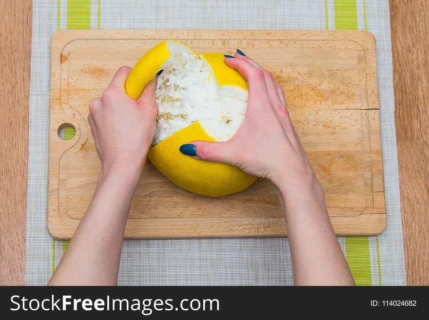 Girl cleaning her hands with pomelo, citrus on a wooden board. Girl cleaning her hands with pomelo, citrus on a wooden board