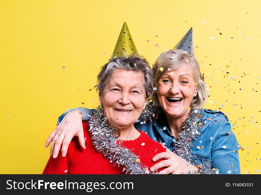 Portrait of a senior women in studio on a yellow background. Party concept. Close up.