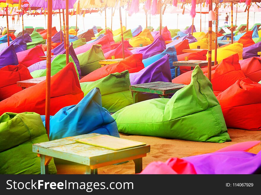 Multicolored bright beach umbrellas, ottomans and tables in the beach cafe. Summer multicolored background