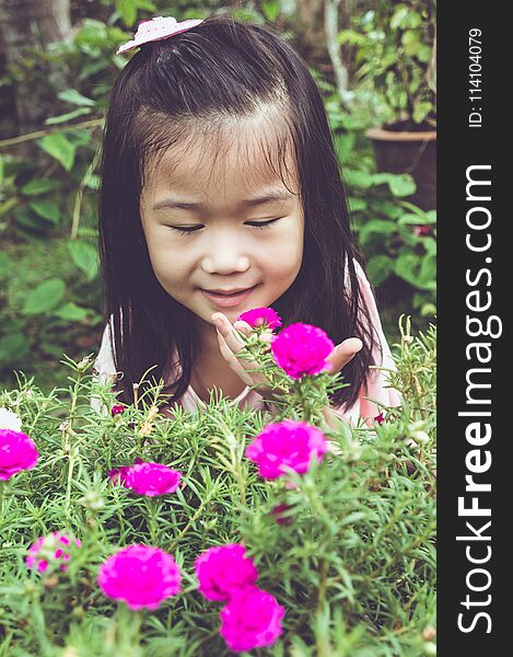 Asian child admiring for pink flowers and nature around at backyard. Vintage tone.