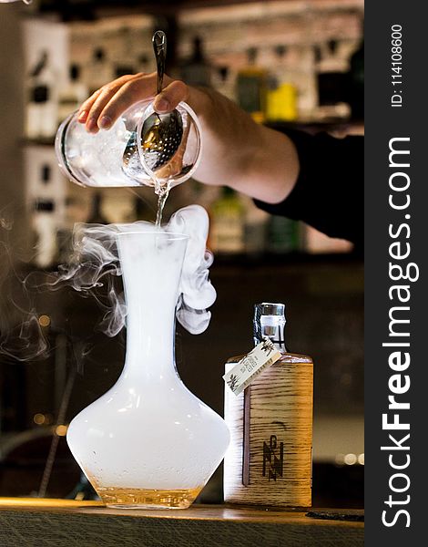 Person Pouring Liquid Into Smoking Glass Container