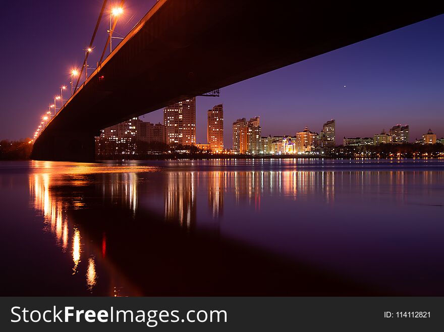 Night city. Beautiful glowing bridge over the river.