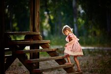 Beautiful Little Girl With Funny Face Expressions Playing, Climbing Up On A Wooden Stairs Royalty Free Stock Images