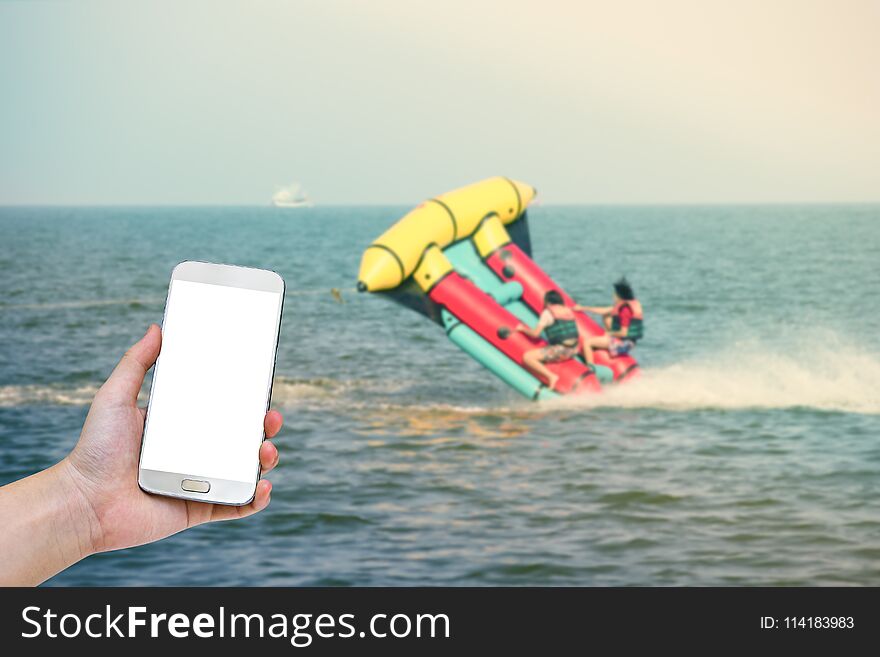 Hand holding mobile smart phone with blurry marine sport background.