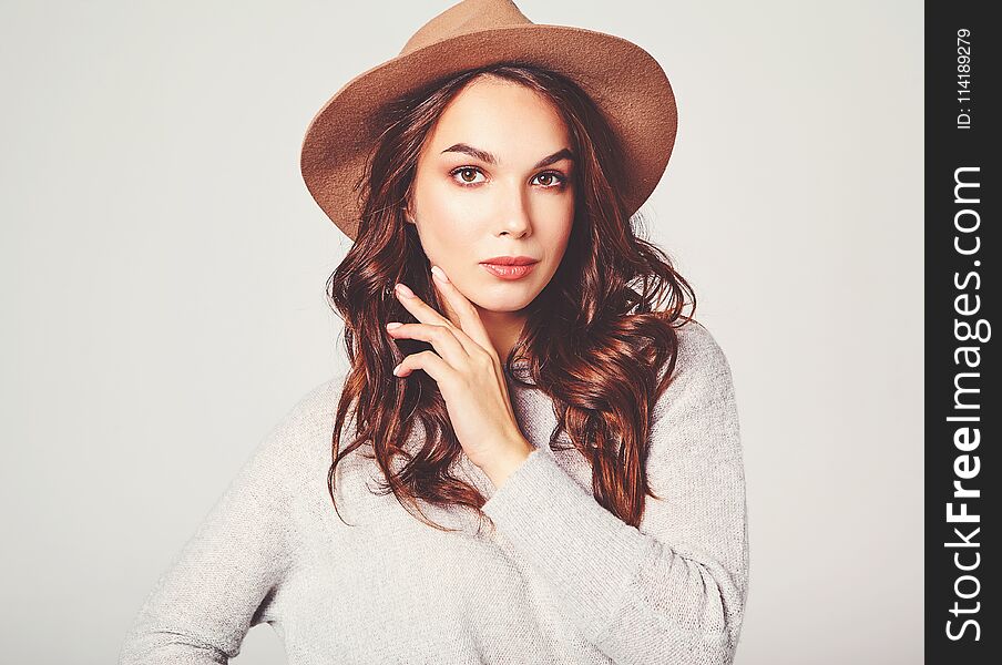 Portrait of young stylish laughing girl model in gray casual summer clothes in brown hat with natural makeup on gray background. Looking at camera. Portrait of young stylish laughing girl model in gray casual summer clothes in brown hat with natural makeup on gray background. Looking at camera