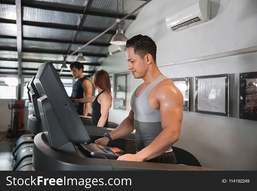 Healthy men start a treadmill together in a sport center. Healthy men start a treadmill together in a sport center