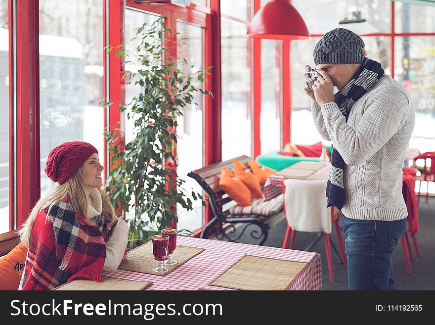 Young photographer with a girl in a cafe
