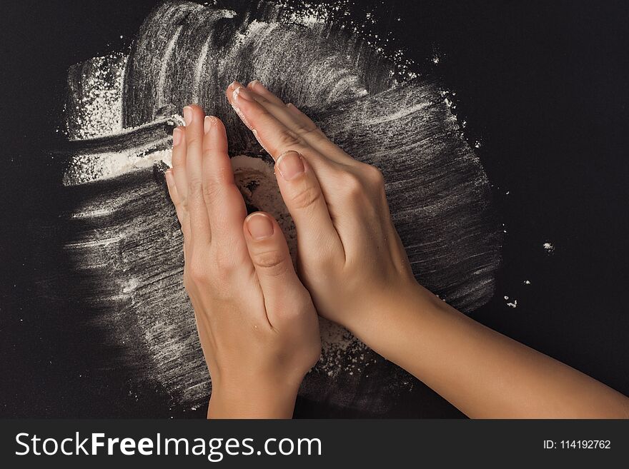 Female hand with flour on a black background. Cooking