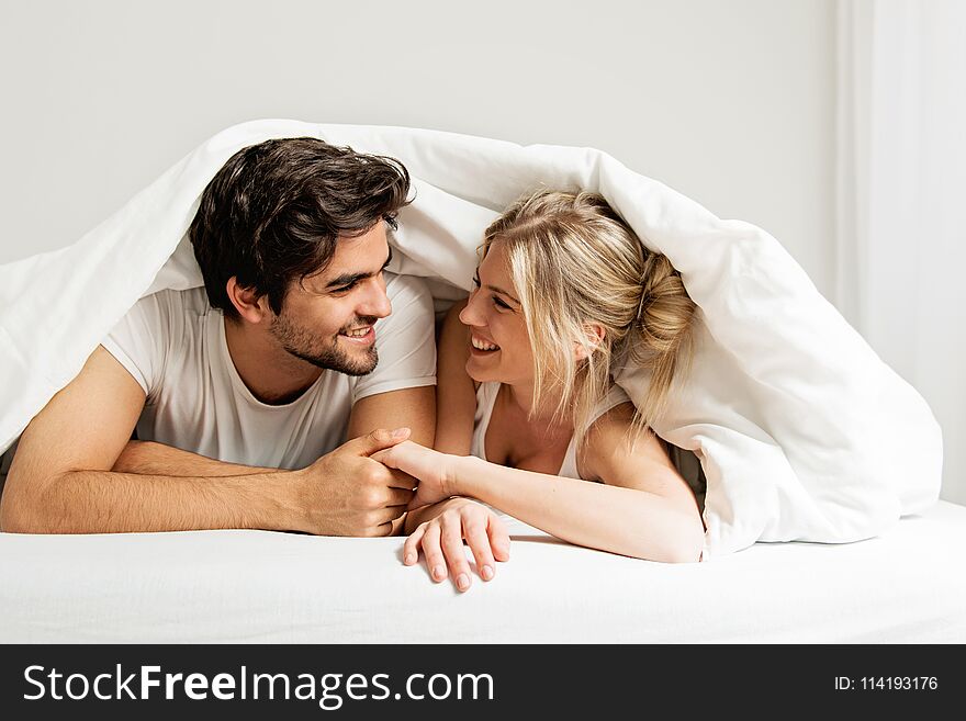 Young loving couple lying on the bed, enjoying, happy