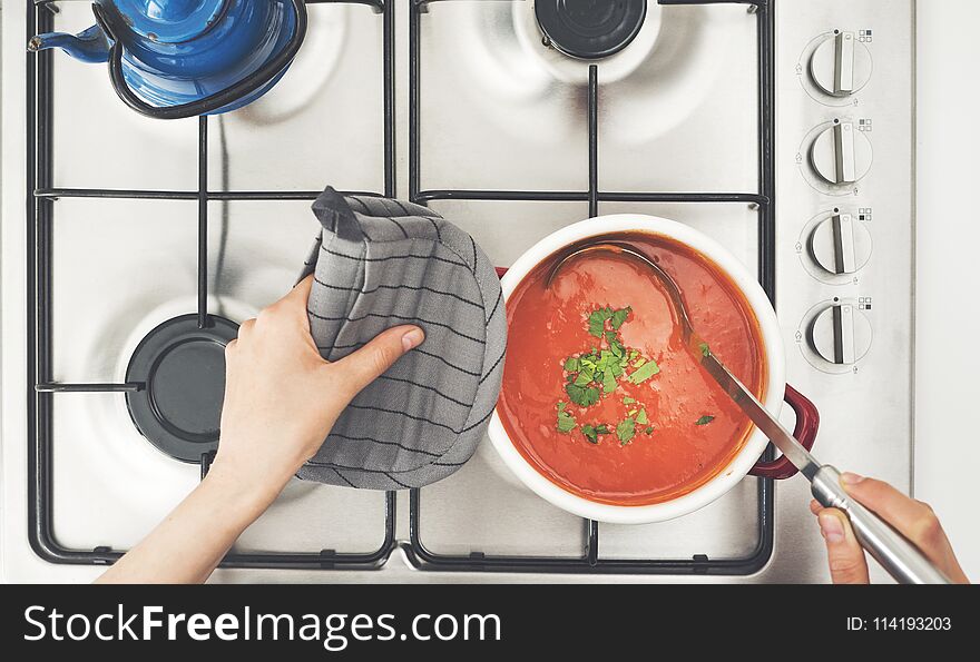 Woman Cooking Tomato Soup On Stove In Kitchen