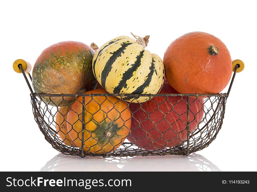 Orange and green pumpkins in vintage basket isolated over white background. Orange and green pumpkins in vintage basket isolated over white background