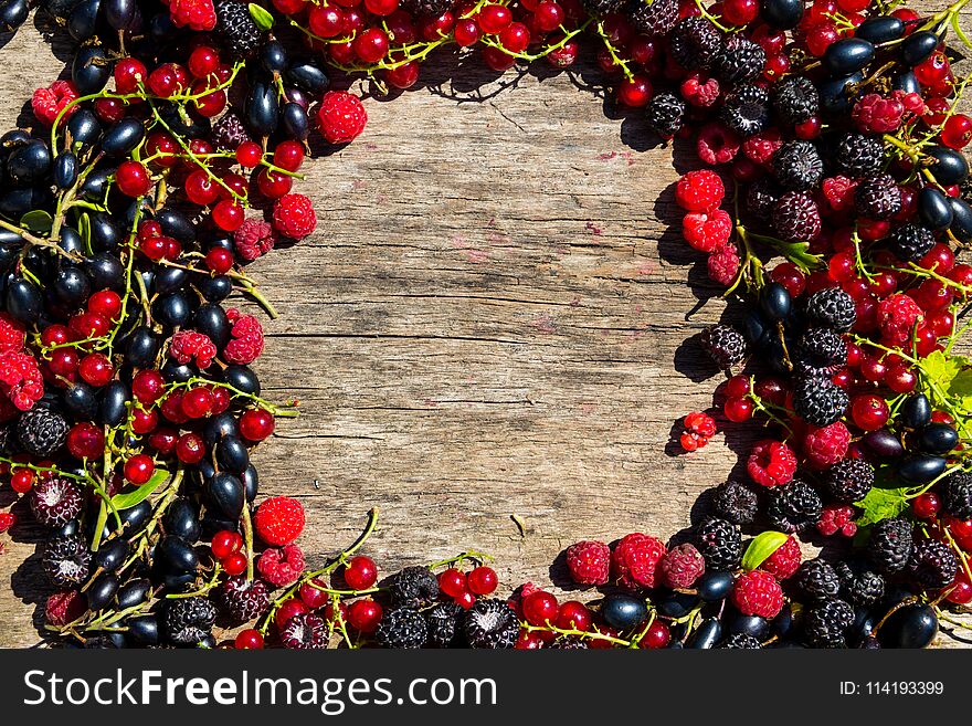 Summer frame with fresh colorful berries on wooden background. Blackberries, raspberries, red and black currant on table. Healthy eating and dieting concept