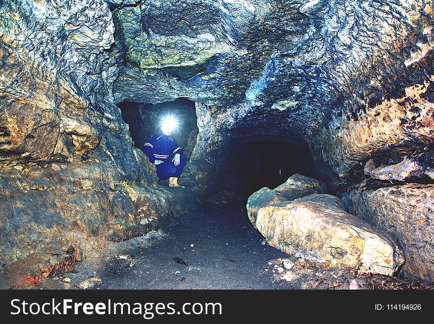 Miner man underground in a mine tunnel. Worker in overalls, safety helmet