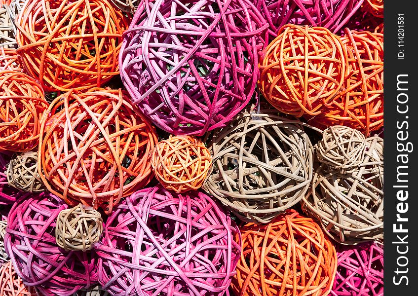 Balls of multicolored straw and thin branches illuminated by bright sunlight. The balls lie in a chaotic manner.