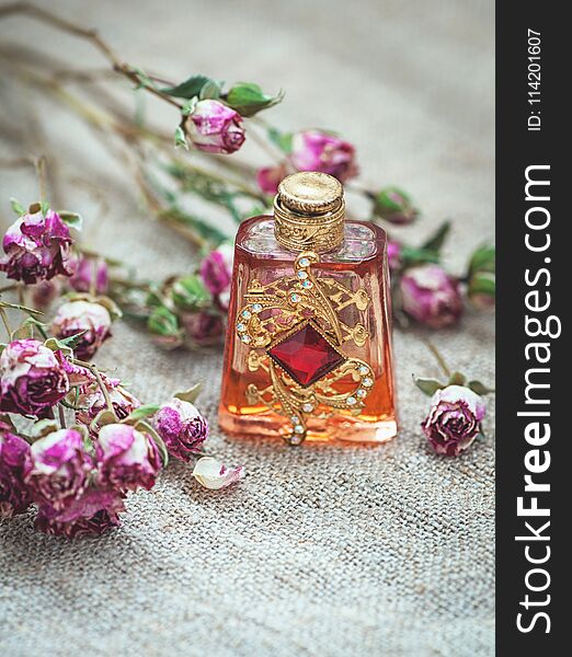 Dry tea roses and vintage perfume bottle on the sackcloth background