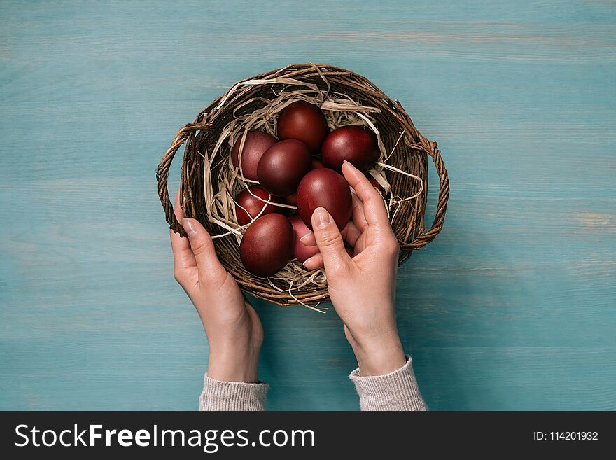 Cropped image of woman putting easter eggs in basket