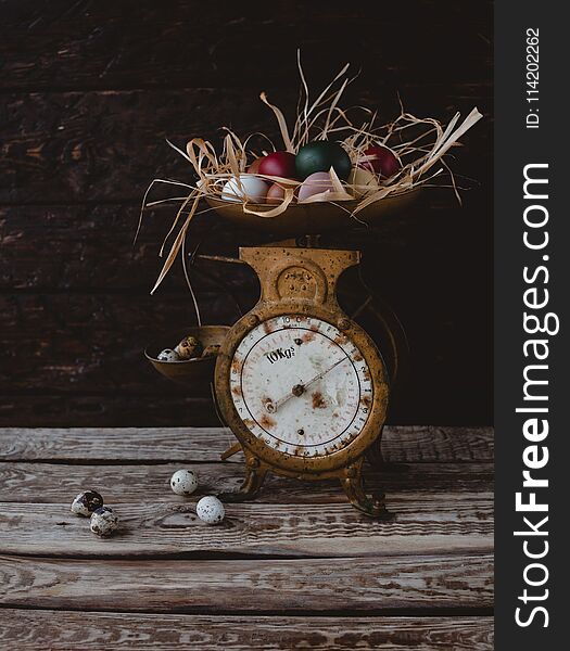 Quail eggs by scales with painted chicken eggs on table