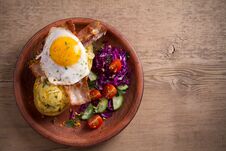 Baked Potato In Jacket Loaded With Cheddar Cheese And Topped With Bacon And Fried Egg In Plate On Wooden Table. Royalty Free Stock Photos Baked Potato In Jacket Loaded With Cheddar Cheese And Topped With Bacon And Fried Egg In Plate On Wooden Table. Royalty Free Stock Photos