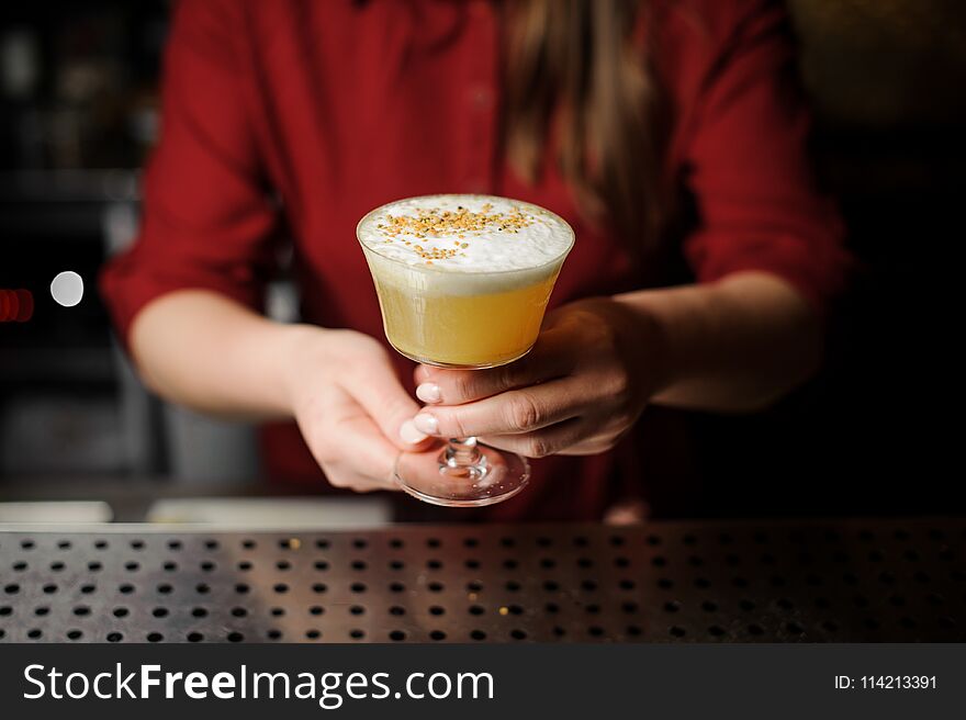 Female bartender serving a fresh delicious decorated yellow cocktail in the beautiful glass on the steel bar counter. Female bartender serving a fresh delicious decorated yellow cocktail in the beautiful glass on the steel bar counter