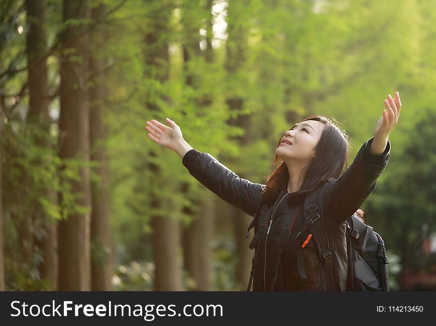 Freedom happy woman feeling alive and free in nature breathing clean and fresh air, carefree young adult dancing in forest or park showing happiness with arms raised up, spring allergies concept. Asian Chinese girl. peach blossom small apple flowering, Freedom happy woman feeling free in nature in spring summer outdoor, with flower in mounth, pink red colorful fun