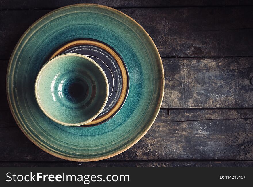 Craft maded empty plates and bowl on the wooden background with blank space. Craft maded empty plates and bowl on the wooden background with blank space