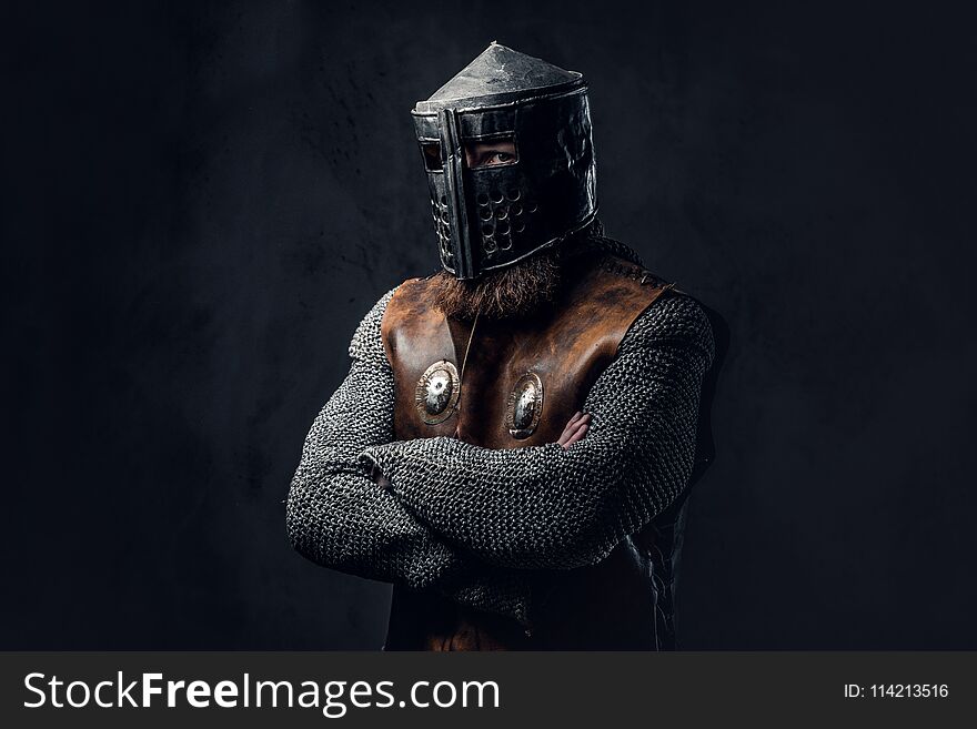 Studio portrait of a male Viking dressed in Nordic armor and an iron helmet over dark grey background. Studio portrait of a male Viking dressed in Nordic armor and an iron helmet over dark grey background.