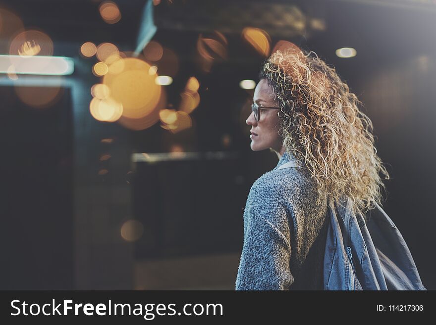 Pretty woman in stylish clothing wearing eye glasses traveling in the european night city. Bokeh and flares effect on blurred background