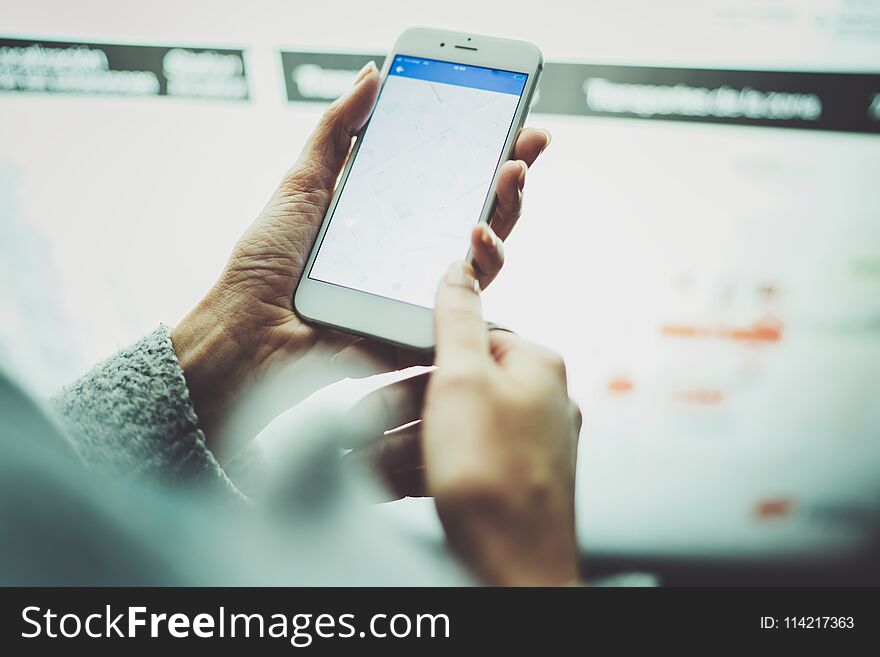 Female hand holding smart phone and using internet for looking new way on electronic city map with night modern blurred background