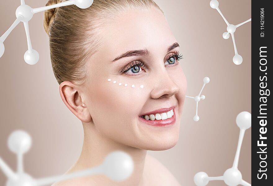 Young woman with cream dots among white molecules. Over beige background.