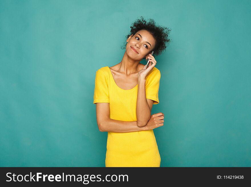 Modern lifestyle and communication. Smiling beautiful african-american woman talking on phone, at blue studio background, copy space. Modern lifestyle and communication. Smiling beautiful african-american woman talking on phone, at blue studio background, copy space