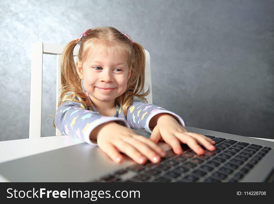 Smiling little girl studying computer. Girl using laptop
