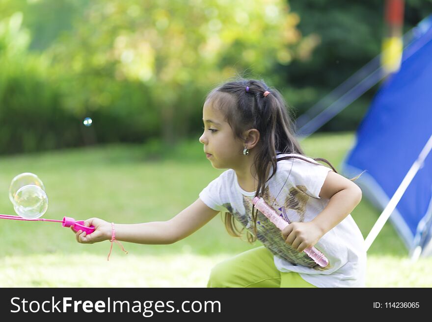 Happy and Beautiful Girl Playing with Soap Bubbles Outdoors. Happy and Beautiful Girl Playing with Soap Bubbles Outdoors