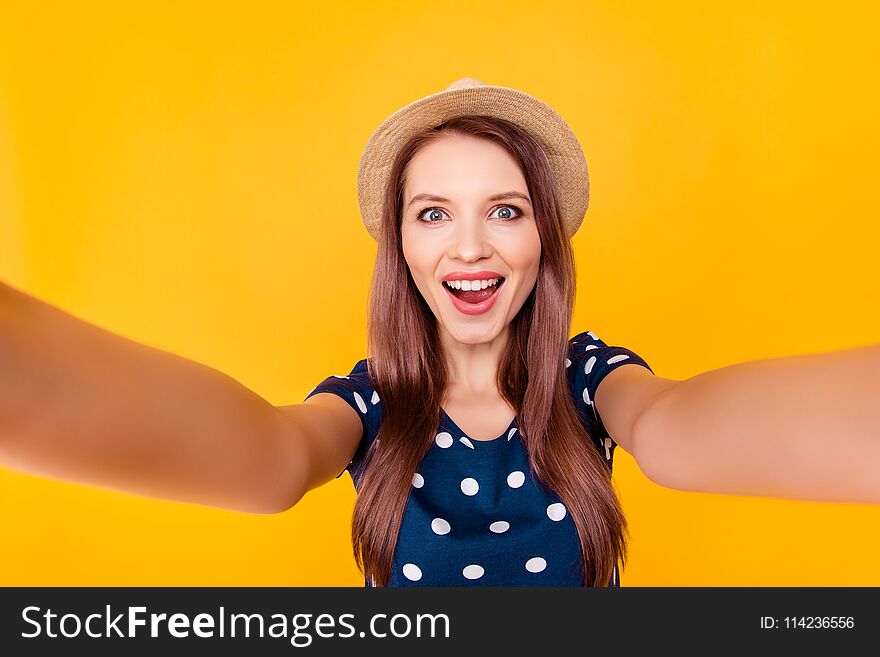 Self portrait of nice, amazing, pretty, positive, laughing, glad woman shooting selfie in two hands on front camera, having polka-dot outfit, isolated on yellow background