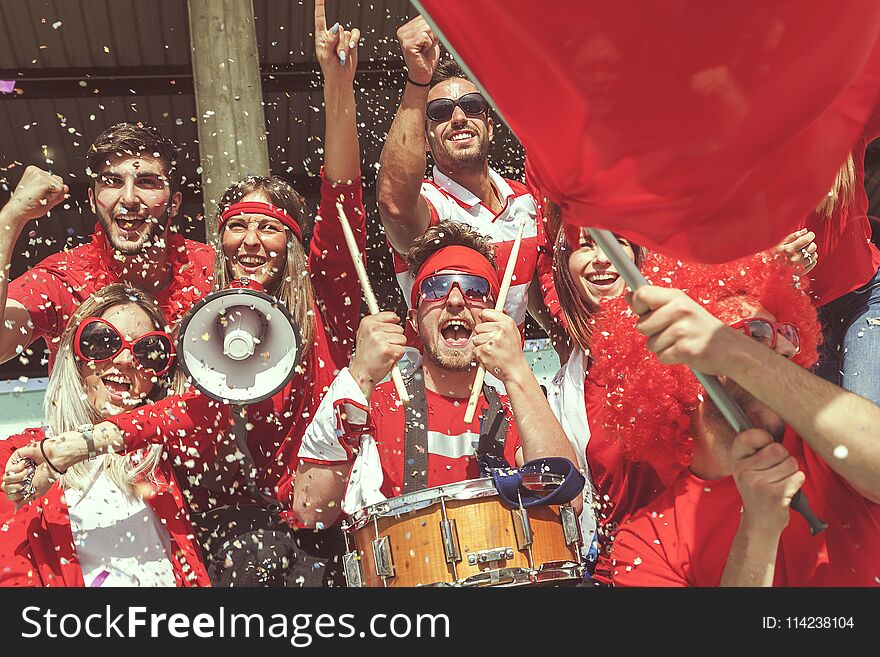 Group of fans dressed in red color watching a sports event