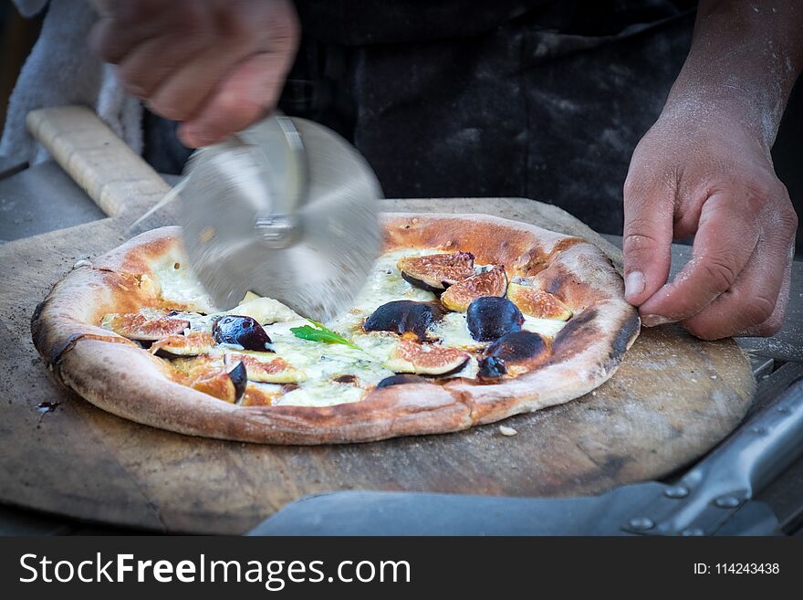 Vegetarian pizza with figs being cut with a cutting wheel. Vegetarian pizza with figs being cut with a cutting wheel