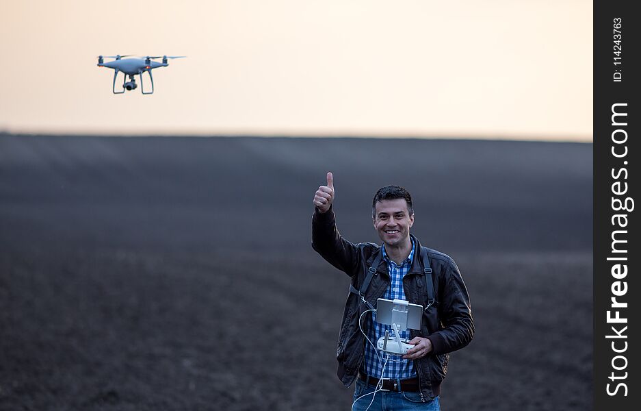 Satisfied farmer navigating drone in field. High technology innovations for increasing productivity in agriculture. Satisfied farmer navigating drone in field. High technology innovations for increasing productivity in agriculture