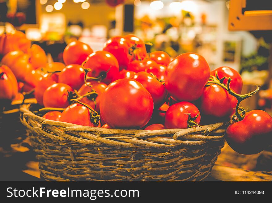 Rustic basket of fresh organic tomatoes on dark background in farmer market.