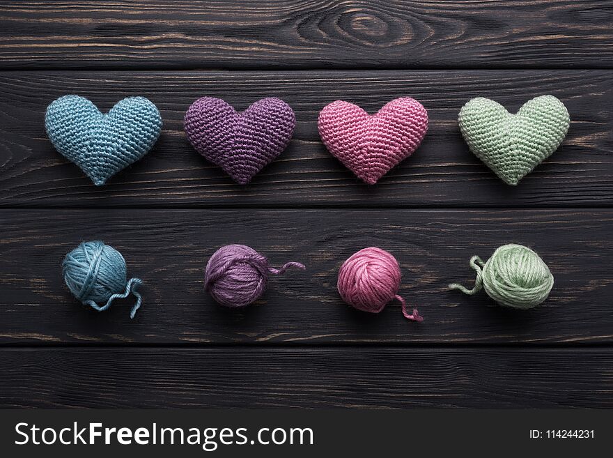 Colorful handicraft crocheted hearts & skeins of yarn on old gray wooden table. Retro color palette. Making a love message. Colorful handicraft crocheted hearts & skeins of yarn on old gray wooden table. Retro color palette. Making a love message