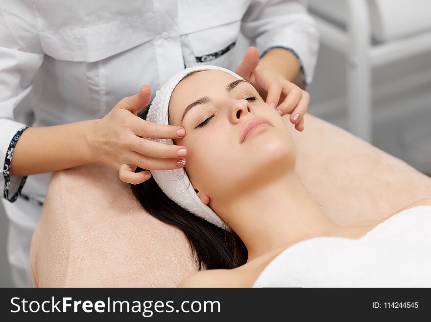 Beautician doing face massage to beautiful brunette.