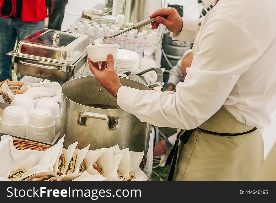 Food outside at an event with attendants in overalls and an apron. Food outside at an event with attendants in overalls and an apron