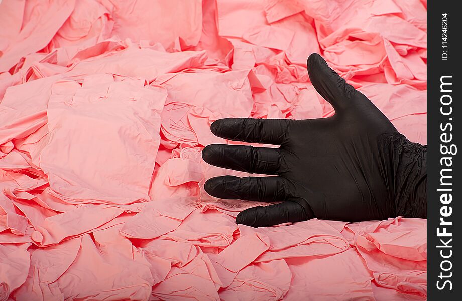 Hand in new black latex medical glove on background of a lot pink rubber gloves close up