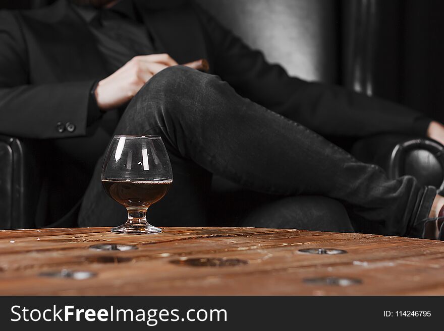 a glass for cognac on a wooden table on the background of a leather chair.