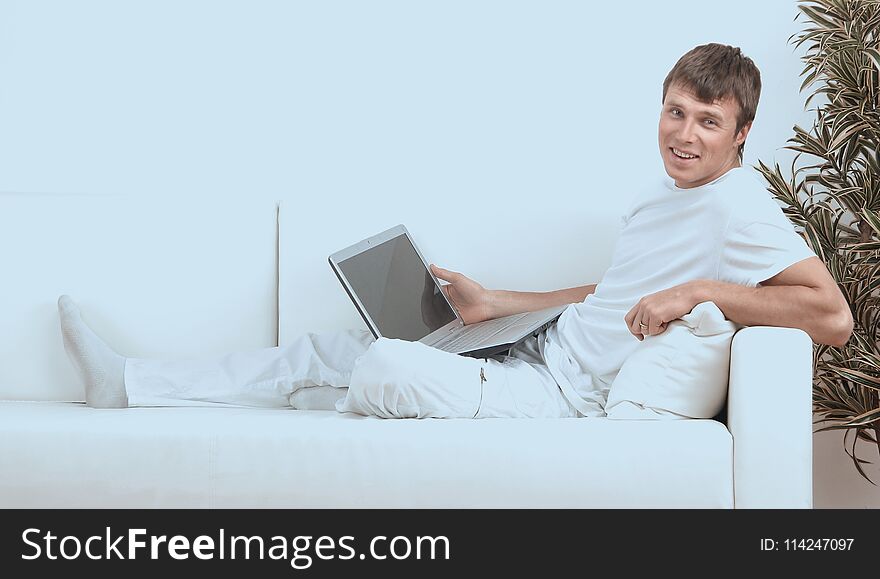 Very Focused Young Man Using Laptop While Sitting Comfortably.