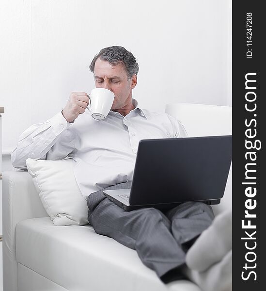 Businessman drinking tea and working on laptop in the hotel room