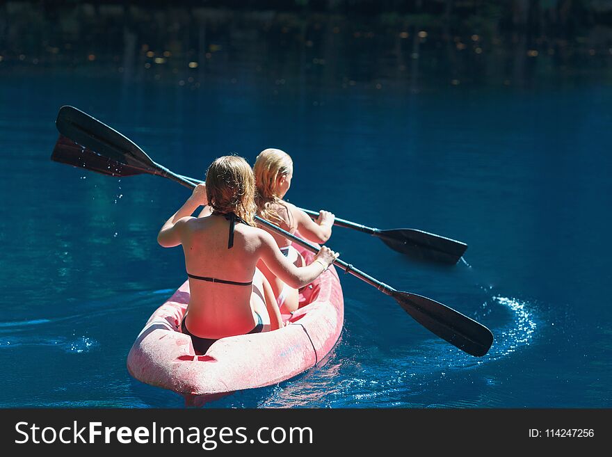 Two girls kayaking on a blue lake, Laguna Dudu